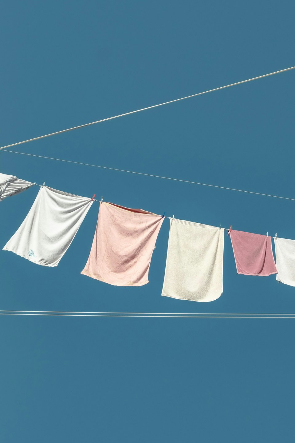 Bunte Kleidung hängt an einer Wäscheleine vor blauem Himmel.